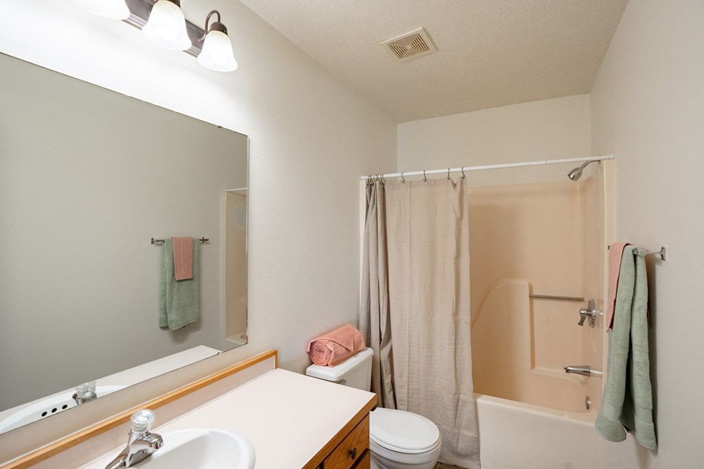 a bathroom with a shower and a sink and a mirror. Fargo, ND Hunters Run 2 Apartments