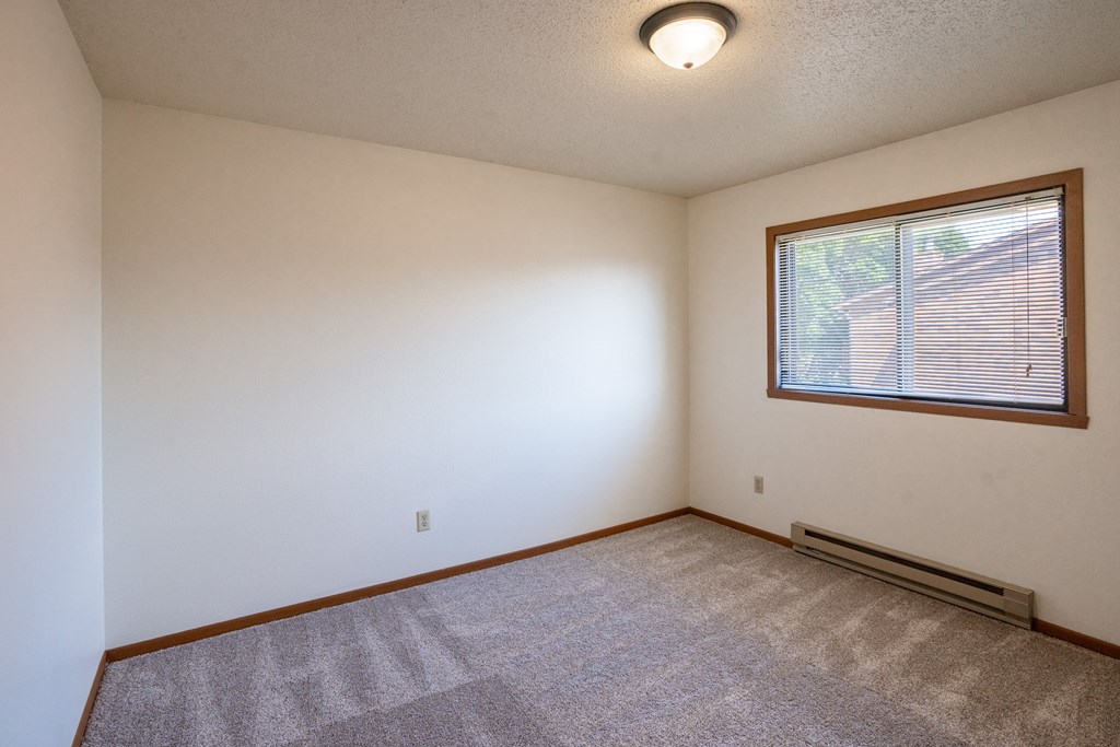 a bedroom with a large window and carpeting