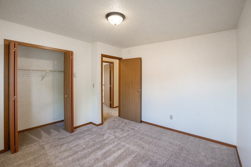 a bedroom of an empty apartment with a door to the closet. Fargo, ND Hunters Run 2 Apartments
