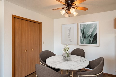 a dining room with a marble table and chairs and a ceiling fan. Fargo, ND Hunters Run 2 Apartments