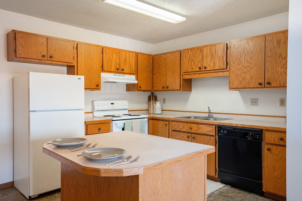 a kitchen with white appliances and wooden cabinets. Fargo, ND Hunters Run 2 Apartments