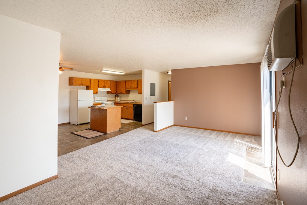 an empty living room with a kitchen in the background. Fargo, ND Hunters Run 2 Apartments