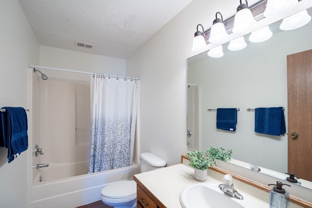 a bathroom with a shower toilet and sink and a mirror. Fargo, ND Kentwood Manor Apartments