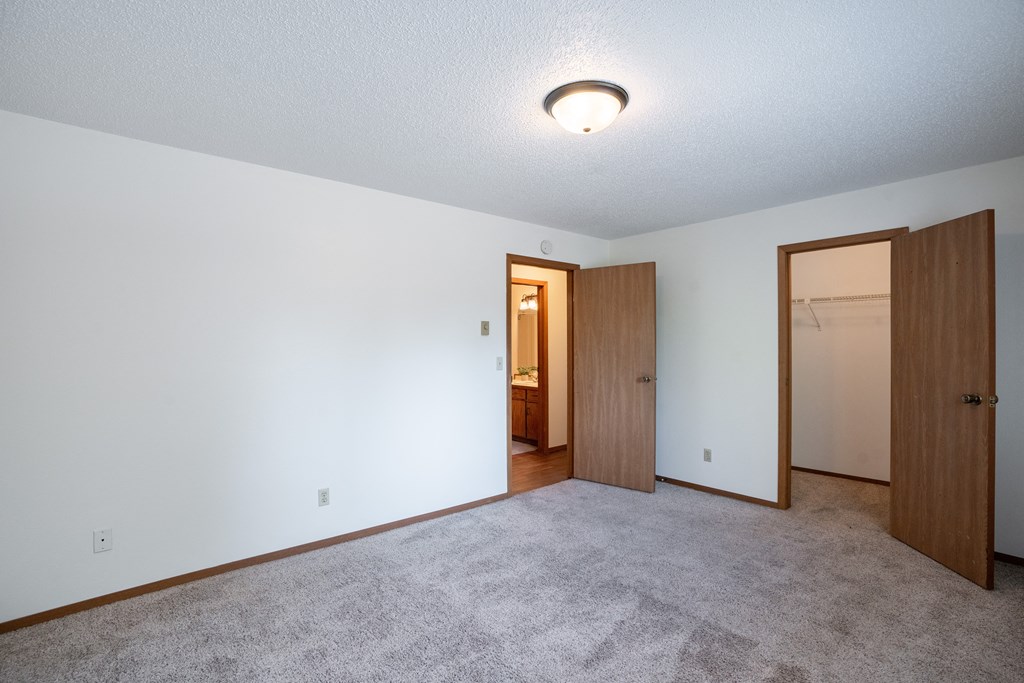 a bedroom with a door to a hallway and a closet. Fargo, ND Kentwood Manor Apartments
