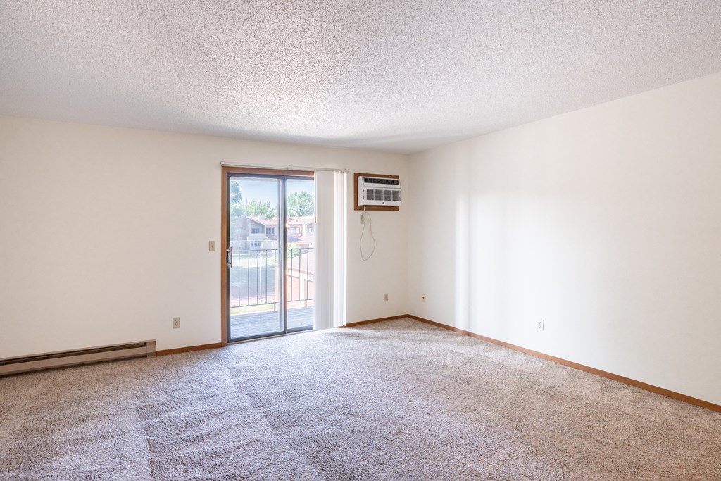an empty living room with a door to a balcony. Fargo, ND Kentwood Manor Apartments