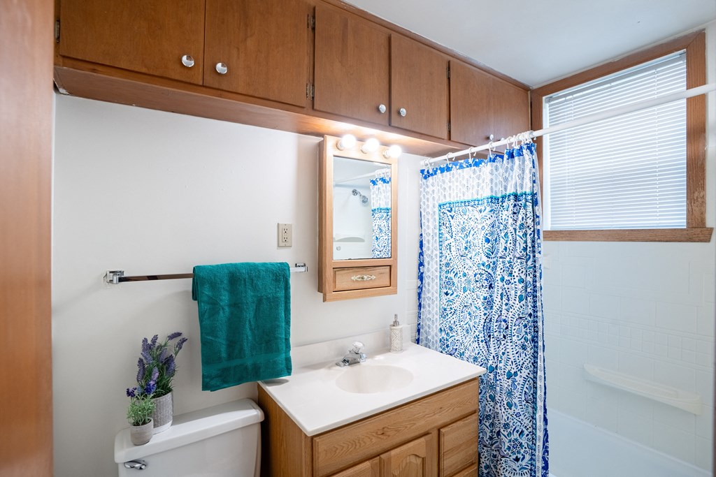 a bathroom with a white sink and a blue shower curtain. Fargo, ND Luxford Apartments