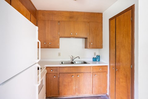a small kitchen with wooden cabinets and a white refrigerator