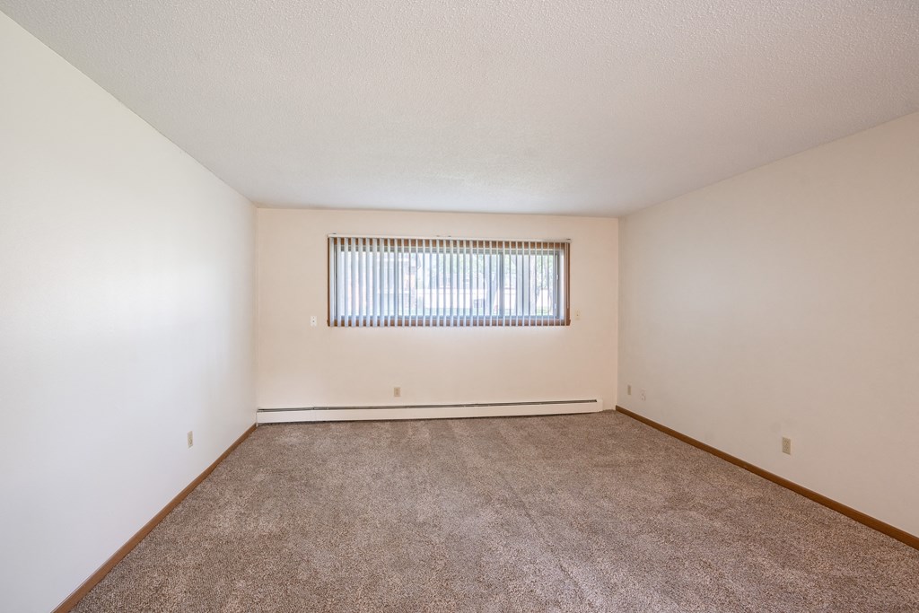 a spacious living room with carpet and a window. Fargo, ND Martha Alice Apartments