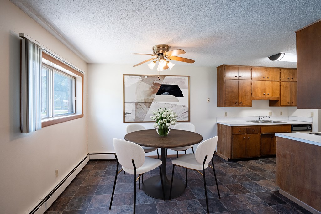 a kitchen and dining room with a table and chairs and a ceiling fan. Fargo, ND Martha Alice Apartments
