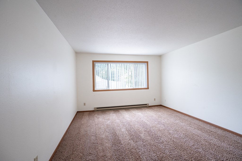 an empty room with carpet and a window. Fargo, ND Monticello Apartments
