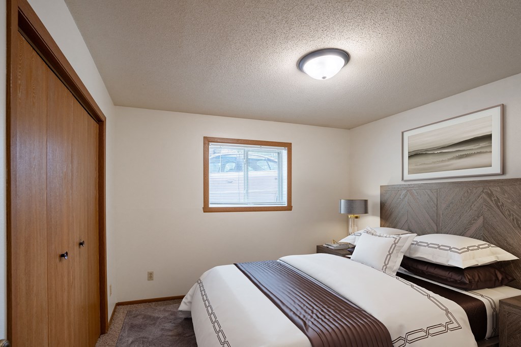 a bedroom with a bed and a closet. Fargo, ND Monticello Apartments