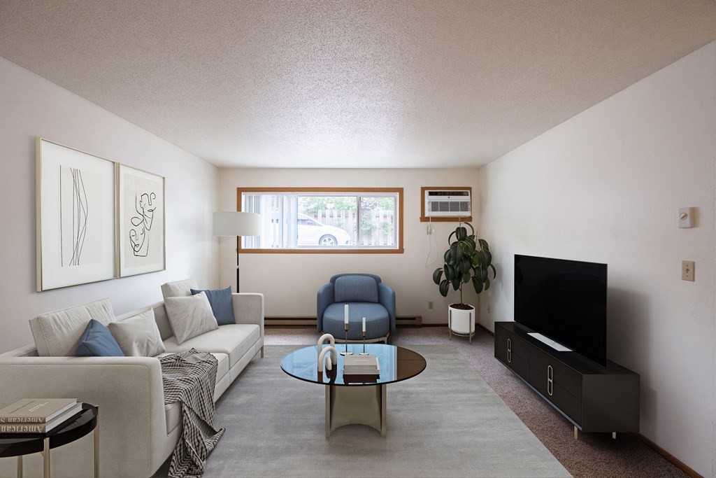 a living room with a couch and a table and a tv. Fargo, ND Monticello Apartments