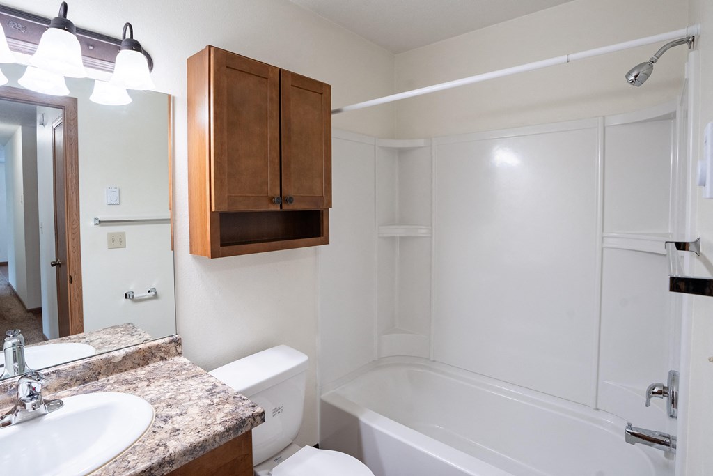 a bathroom with a sink and a toilet and a bath tub. Fargo, ND Monticello Apartments