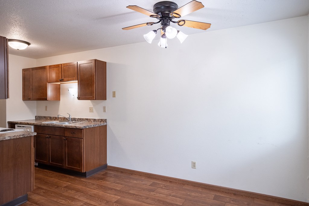 an empty kitchen with wooden cabinets and a ceiling fan. Fargo, ND Monticello Apartments