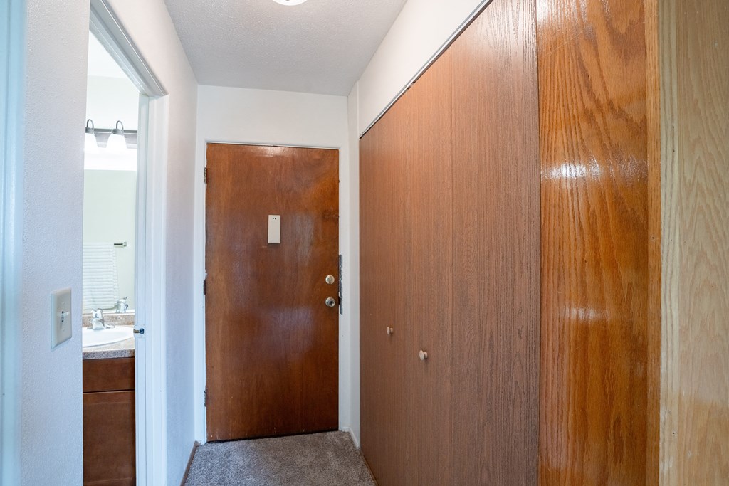 a hallway with a wooden door and a bathroom with a sink. Fargo, ND Morningside Apartments