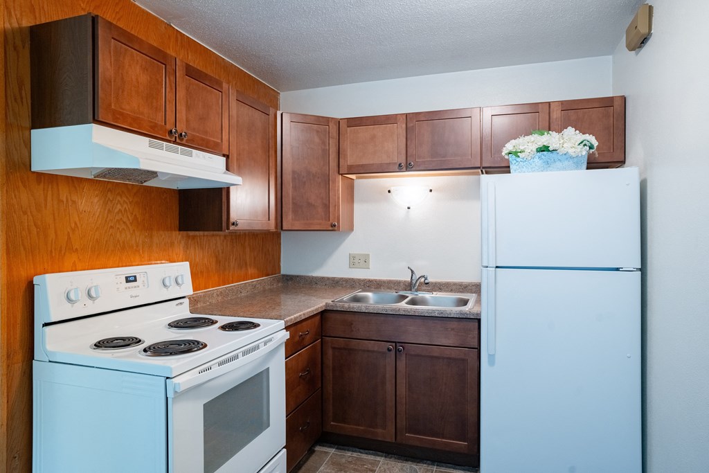 an empty kitchen with white appliances and wooden cabinets. Fargo, ND Morningside Apartments
