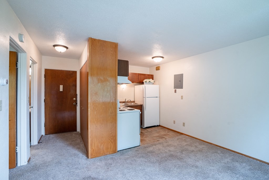 an empty living room with a kitchen with a refrigerator and a sink. Fargo, ND Morningside Apartments