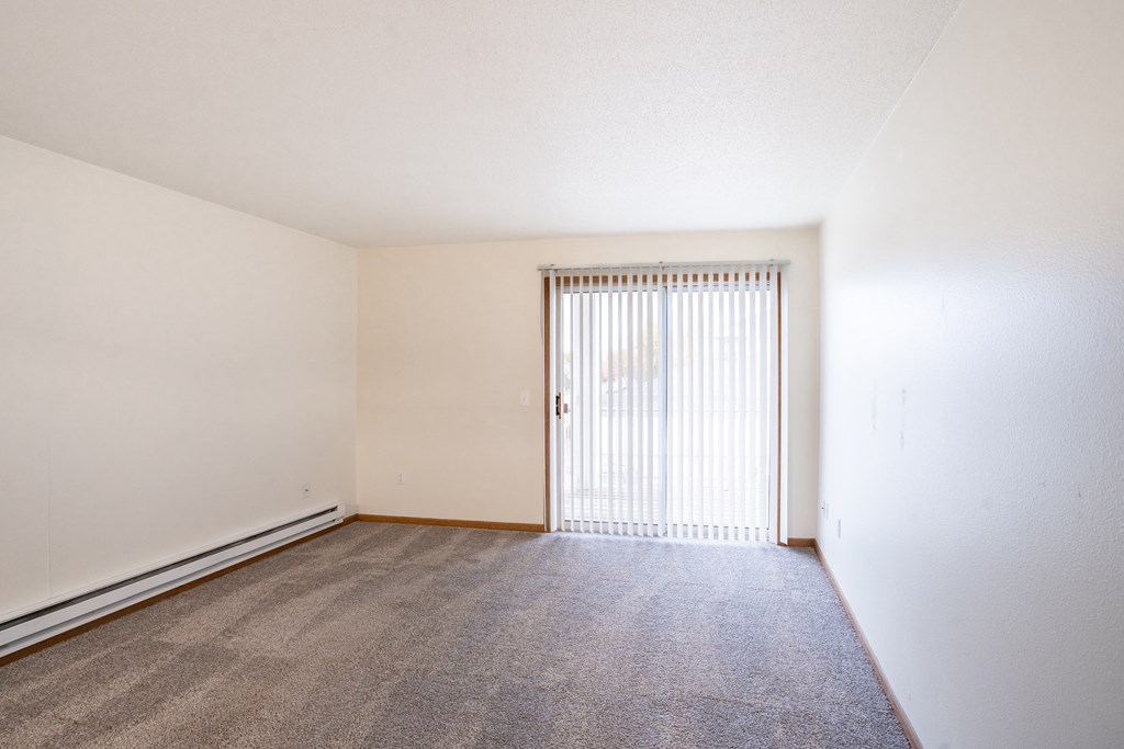 the spacious living room of an apartment with a door to the balcony. Fargo, ND Oxford Apartments