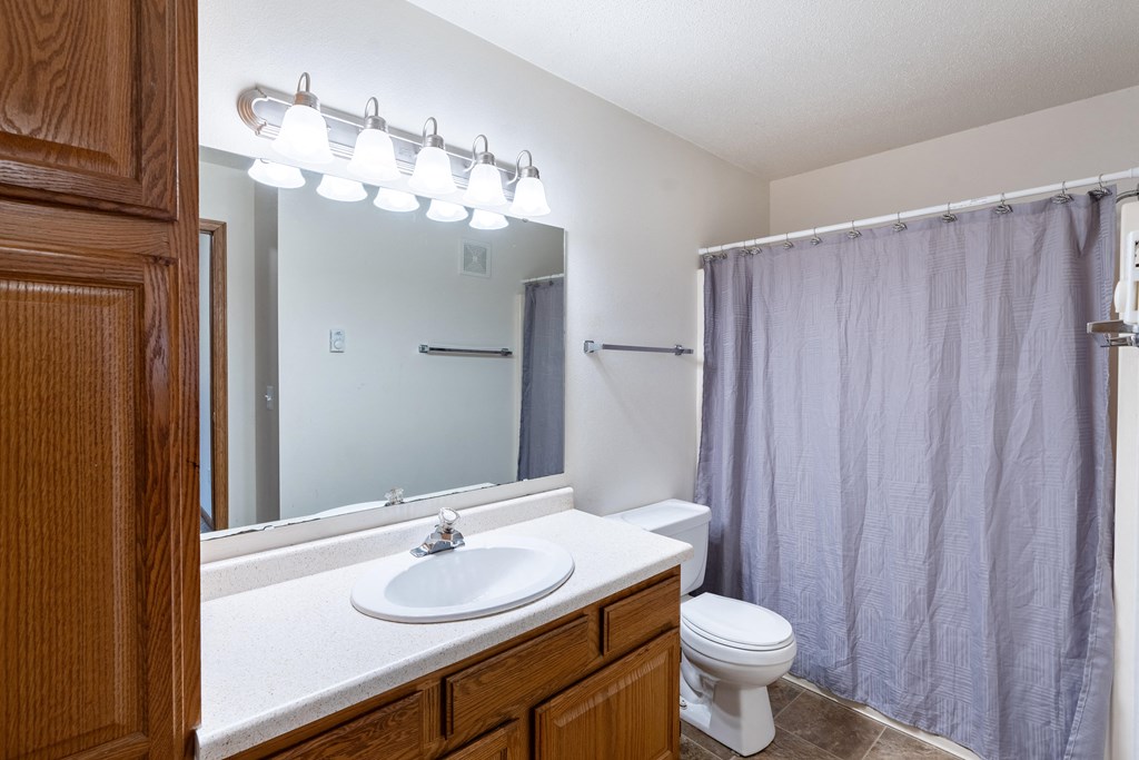a bathroom with a shower toilet and sink and a mirror. Fargo, ND Oxford Apartments