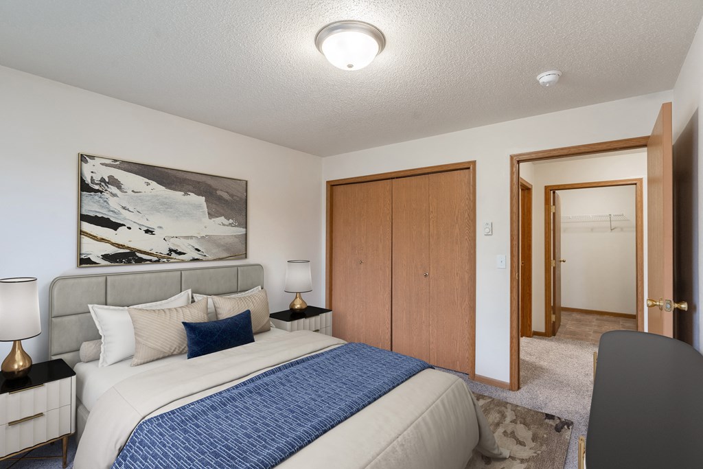 a bedroom with a bed and a closet and a door to a bathroom. Fargo, ND Oxford Apartments