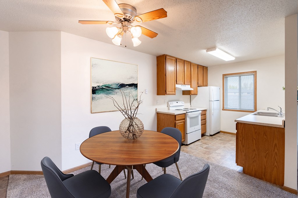 a dining room with a table and chairs and a kitchen. Fargo, ND Oxford Apartments
