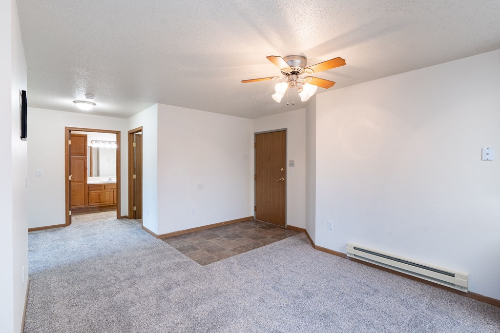 the living room and dining room of an empty house with a ceiling fan. Fargo, ND Oxford Apartments