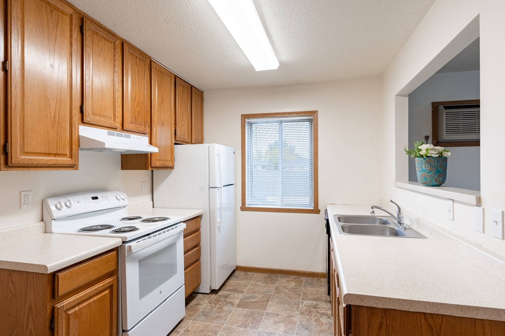 a kitchen with white appliances and wooden cabinets. Fargo, ND Oxford Apartments