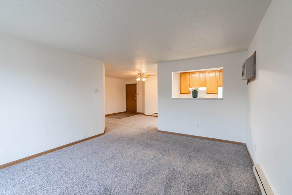 the living room and dining room of an apartment with white walls and carpet. Fargo, ND Oxford Apartments