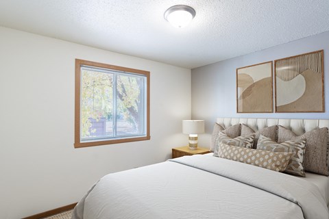 a bedroom with a large bed and a window. Fargo, ND Pacific Park Apartments