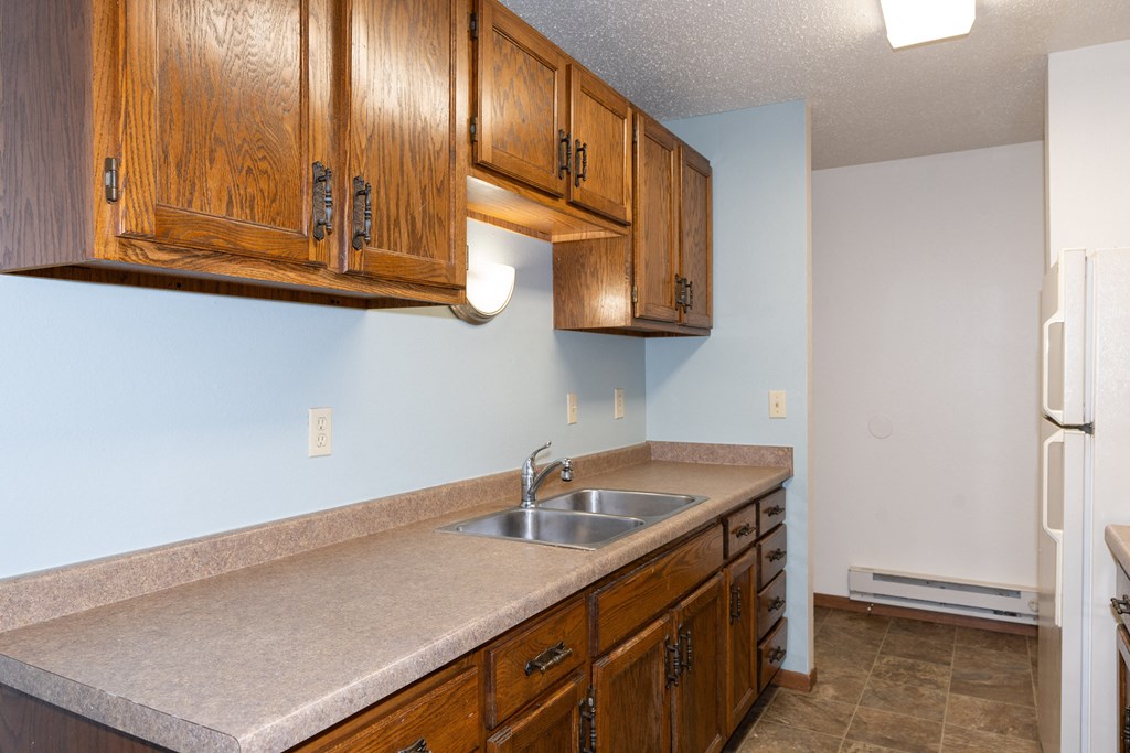 a kitchen with a sink and cabinets and a refrigerator. Fargo, ND Pacific South Apartments