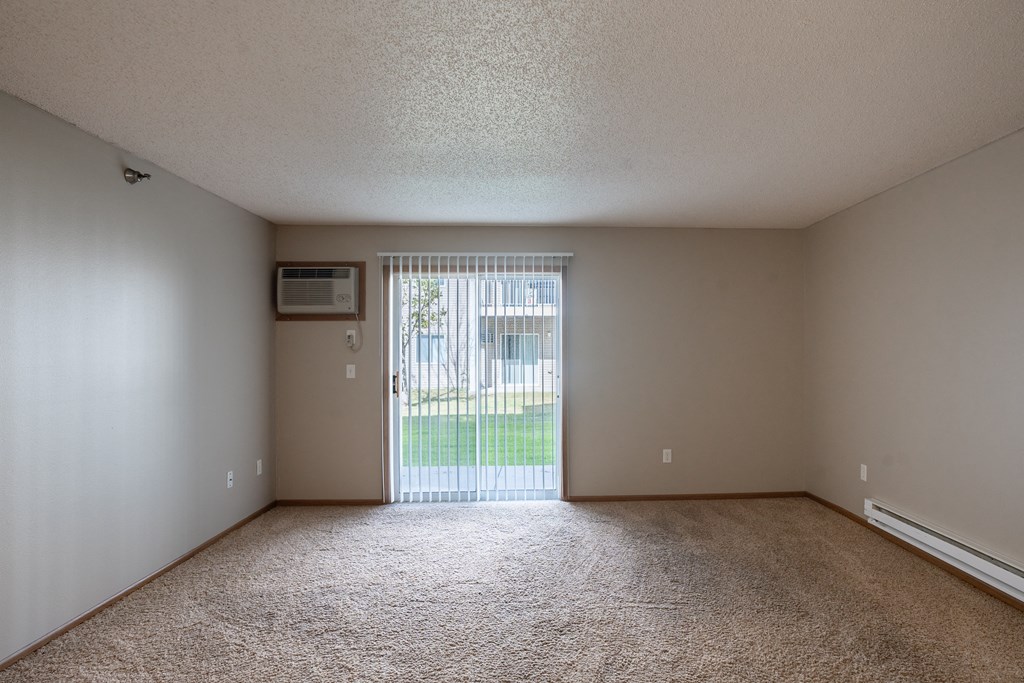 an empty living room with a sliding glass door to a yard