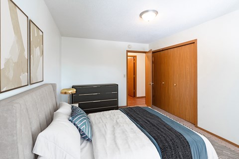 a bedroom with a bed and a closet and a door to a bathroom. Fargo, ND Rosegate Apartments