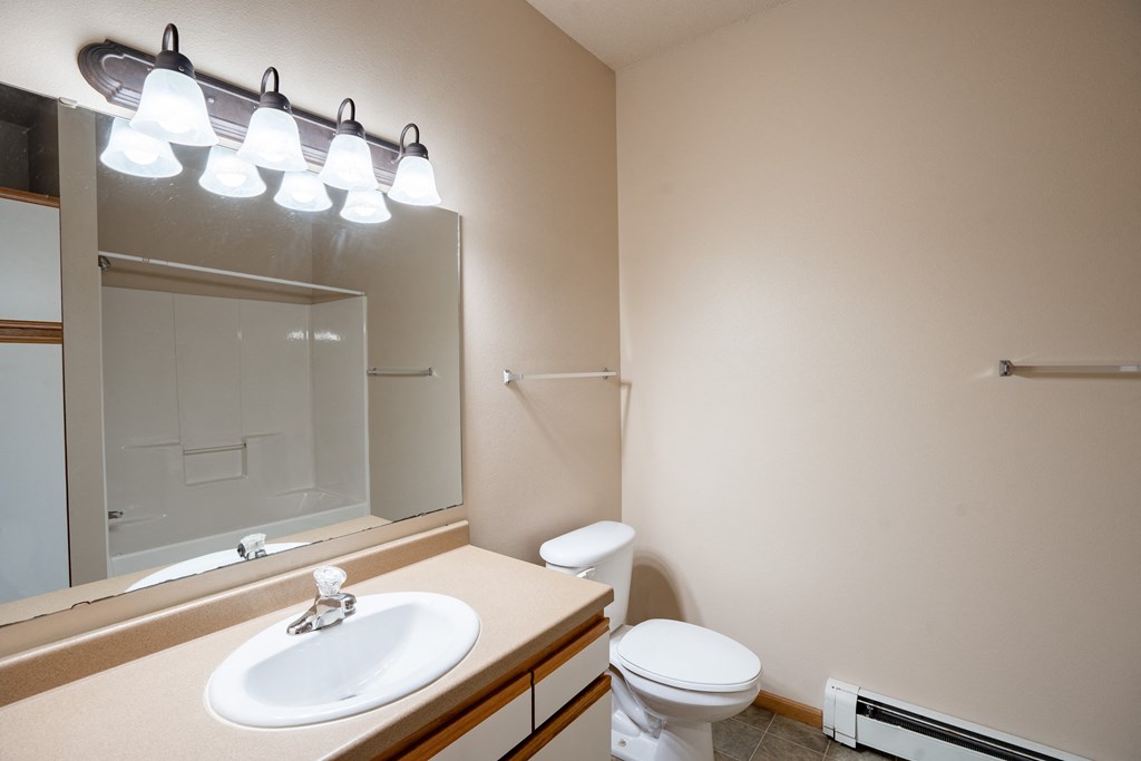 a bathroom with a sink and a mirror and a toilet. Fargo, ND West Lake Apartments