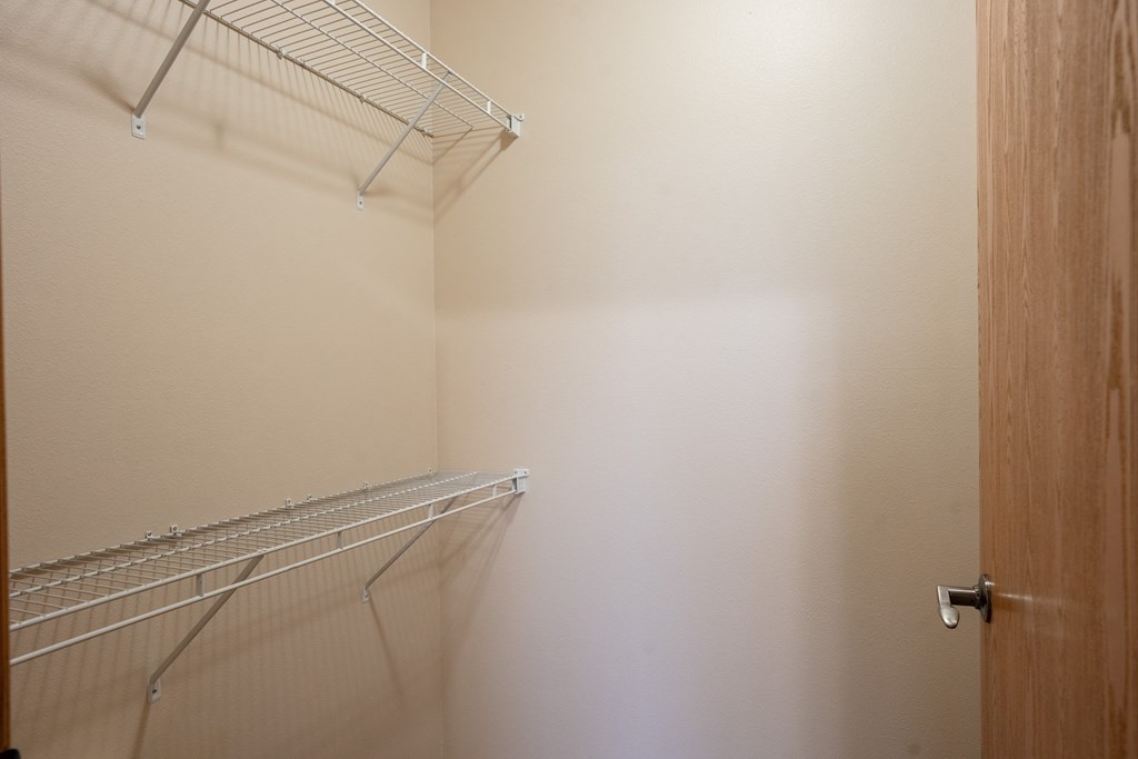 a walk in closet with a white wall and a wire rack on the wall. Fargo, ND West Lake Apartments