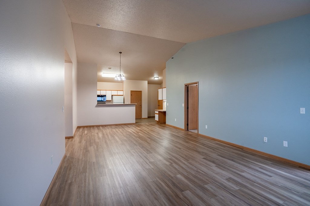 the living room and dining area of an empty apartment with wood floors and blue walls. Fargo, ND West Lake Apartments