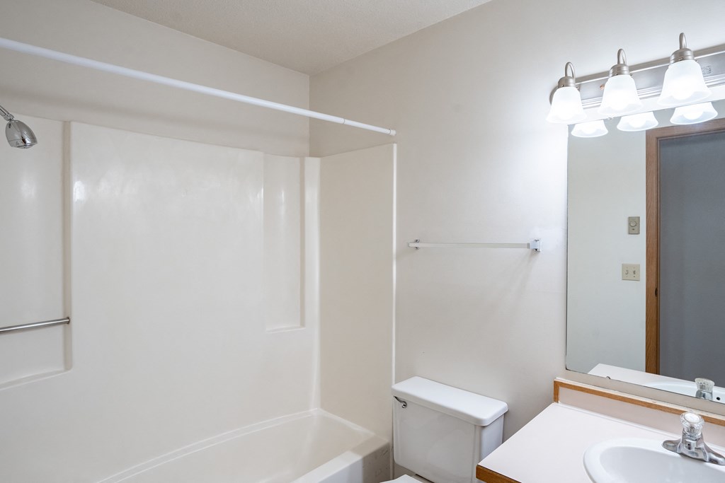 a bathroom with a toilet and a sink and a mirror. Fargo, ND Westview Towers Apartments