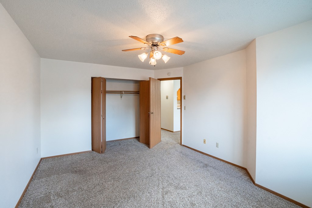 a bedroom with a closet and ceiling fan. Fargo, ND Westview Towers Apartments | Bedroom