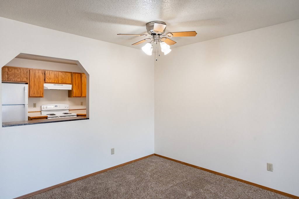 an empty room with a ceiling fan and a kitchen. Fargo, ND Westview Towers Apartments