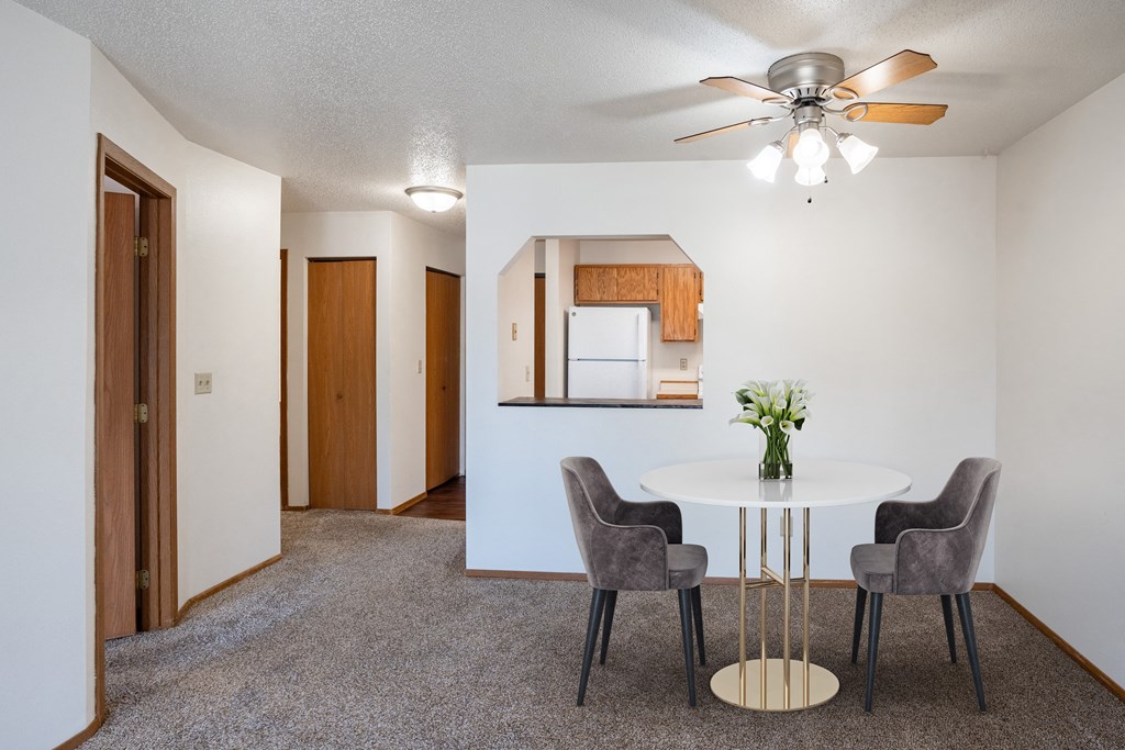 our living room and dining room with a white table and chairs and a ceiling fan. Fargo, ND Westview Towers Apartments