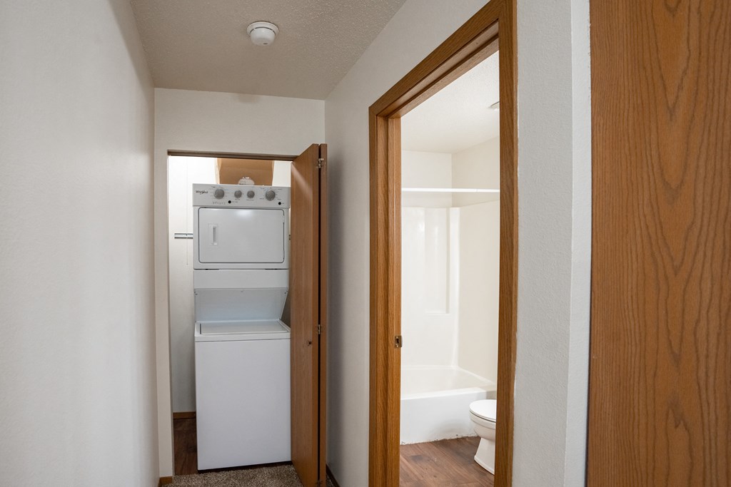 a hallway with a door to a room with a washer and dryer and a laundry room with a. Fargo, ND Westview Towers Apartments