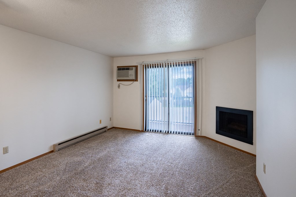 an empty living room with a fireplace and a sliding glass door. Fargo, ND Westview Towers Apartments