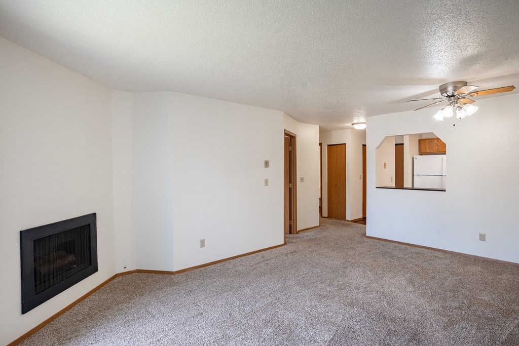 an empty living room with a fireplace and a ceiling fan. Fargo, ND Westview Towers Apartments
