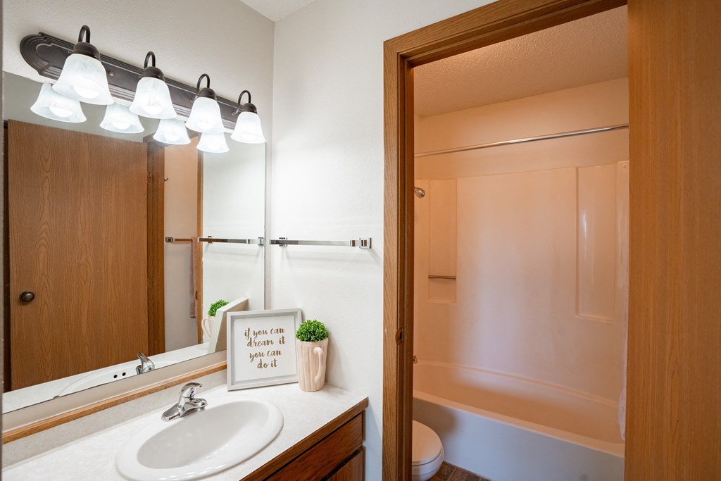 a bathroom with a mirror and a sink and a shower. Fargo, ND Westview Towers Apartments