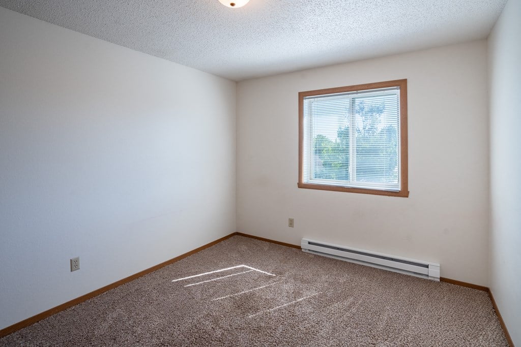 a bedroom with a window and carpeted floors. Fargo, ND Westview Towers Apartments