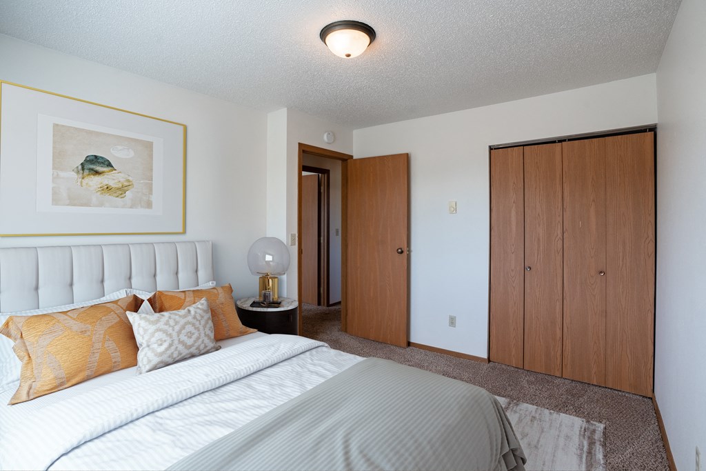 a bedroom with a bed and a closet. Fargo, ND Westview Towers Apartments