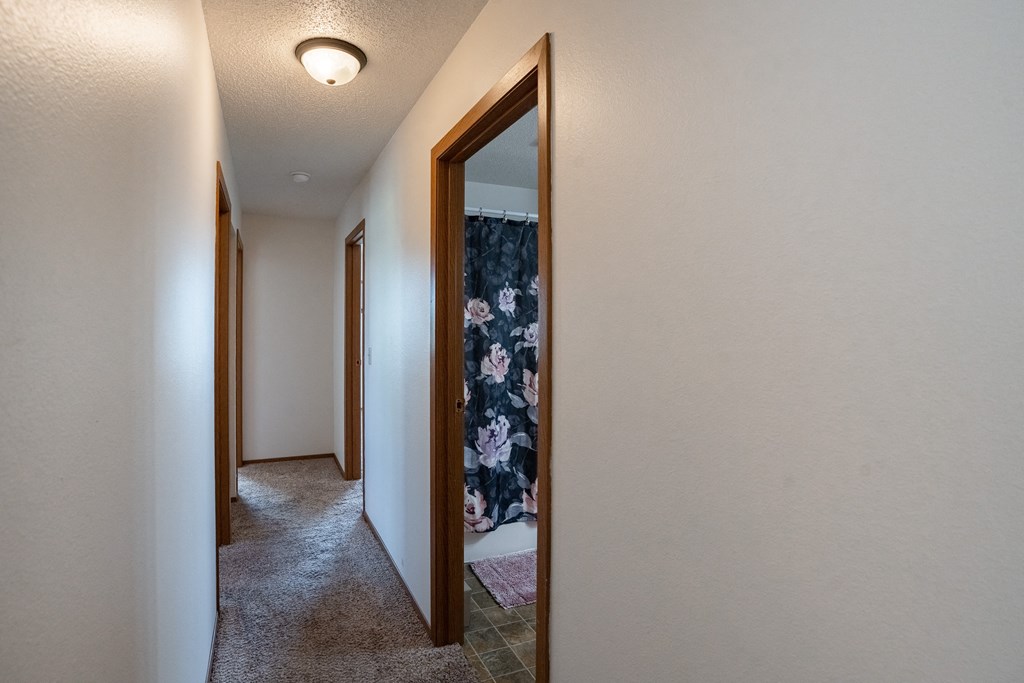 a hallway with a closet and a mirror in a house. Fargo, ND Westview Towers Apartments