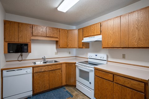 an empty kitchen with white appliances and wooden cabinets. Fargo, ND Westview Towers Apartments