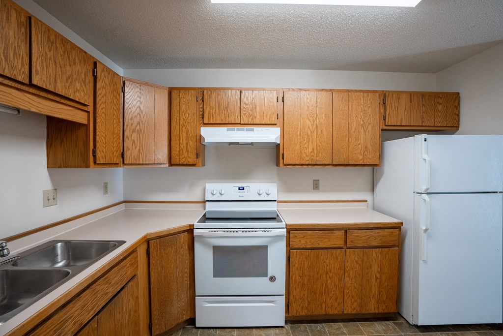an empty kitchen with white appliances and wooden cabinets. Fargo, ND Westview Towers Apartments
