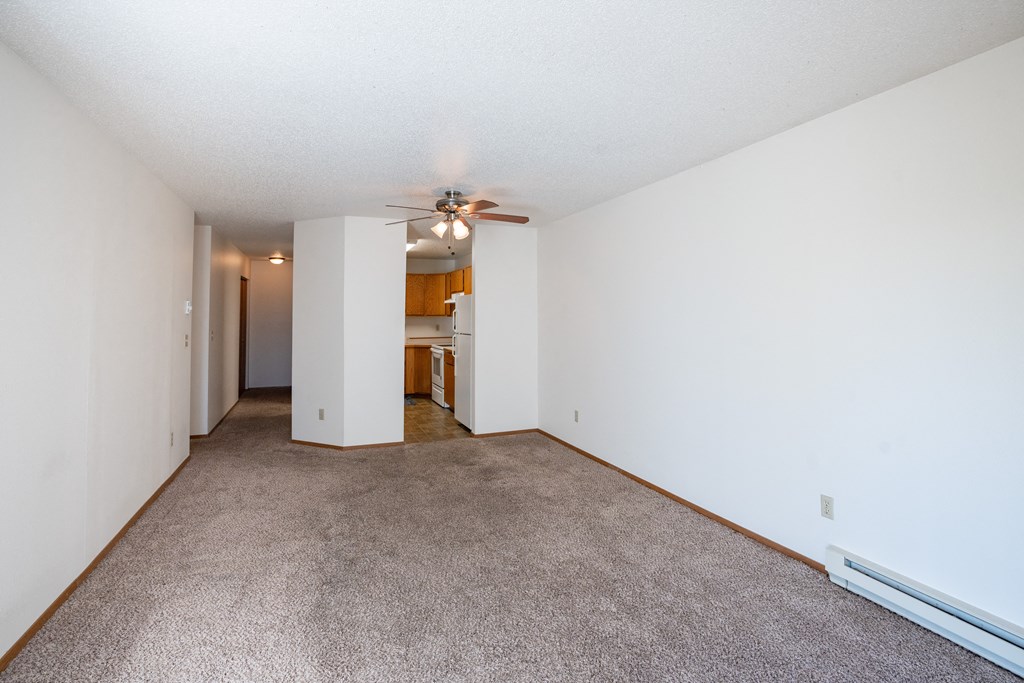 a spacious living room with carpet and a ceiling fan. Fargo, ND Westview Towers Apartments