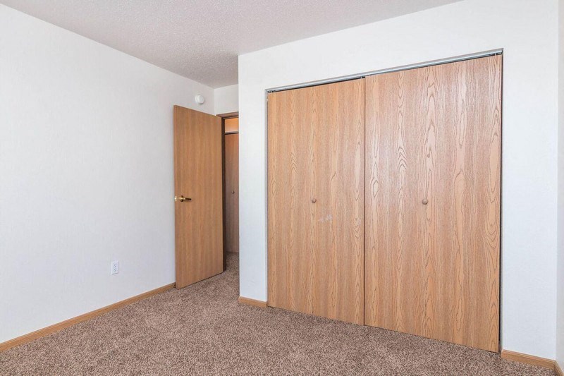 an empty bedroom with a closet and a door to a hallway. Fargo, ND Foxtail Townhomes